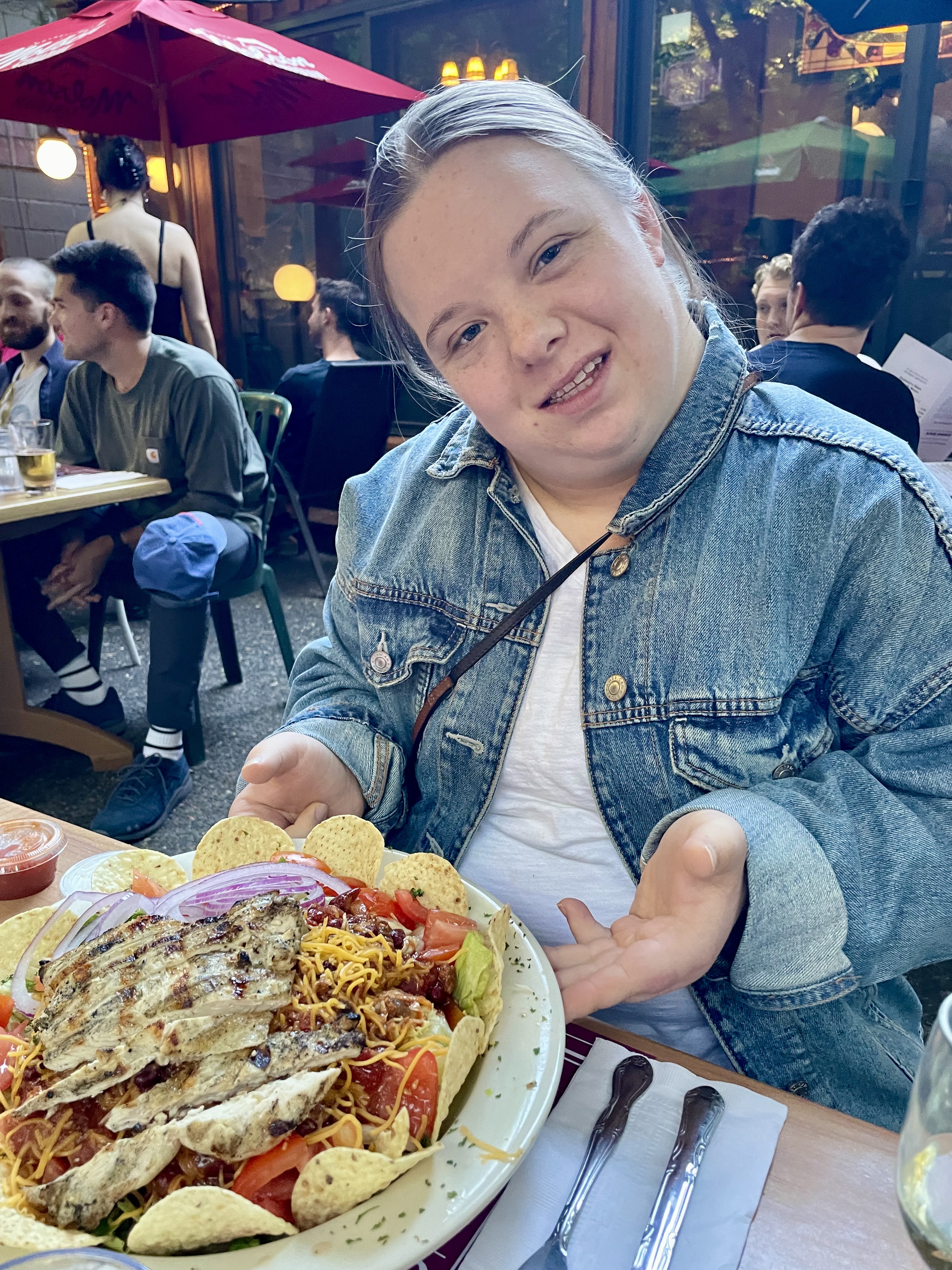 image description: Genevieve's hands hold onto a plate of a restaurant dish of mexican salad. 