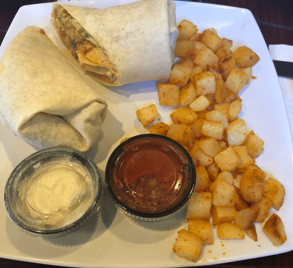 image description: my plate of food from the Poked Yolk had a burrito, breakfast potatoes, and two sides of salsa and sour cream.