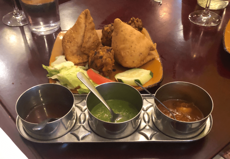 image description: a plate of samosas and three dipping sauces