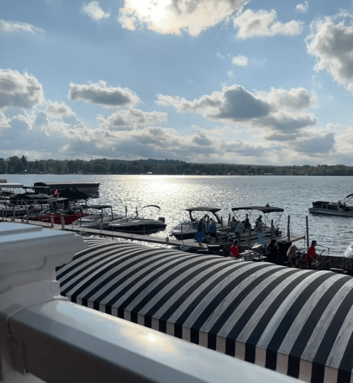 alt text: the sun is setting over the lake and the boats at the dock